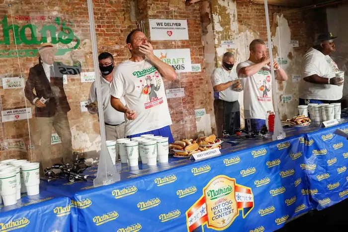 Competitive eater Joey Chestnut, center left, sets a new world record with 75 hot dogs to win the men's division of the Nathan's Famous July Fourth hot dog eating contest.